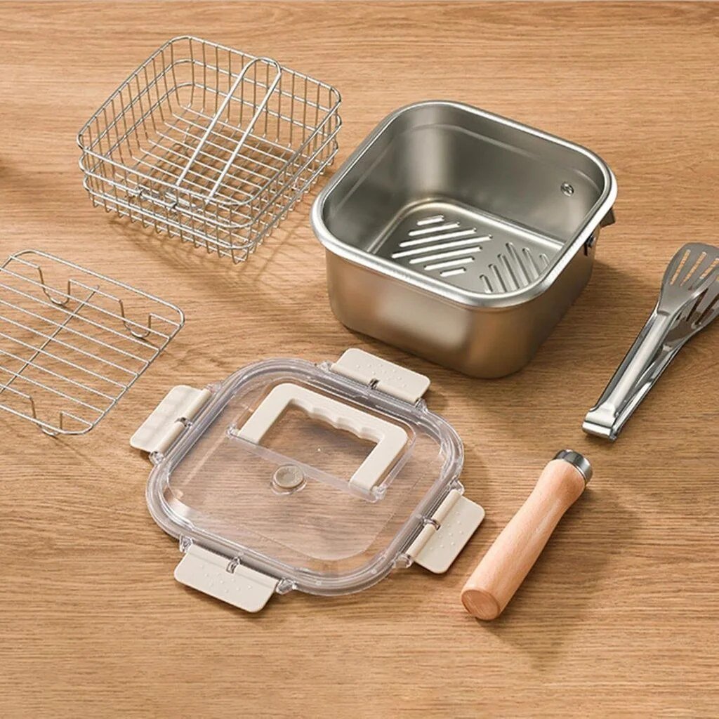 Everything in the box laid out on a wooden table: pot, frying basket, draining rack, clip-lock lid, tongs and wooden handle
