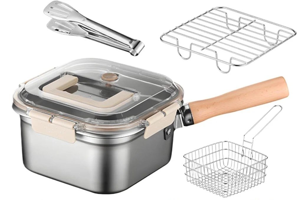Square stainless steel pot with clear clip-lock lid and wooden handle, shown with a wire frying basket, draining rack and tongs